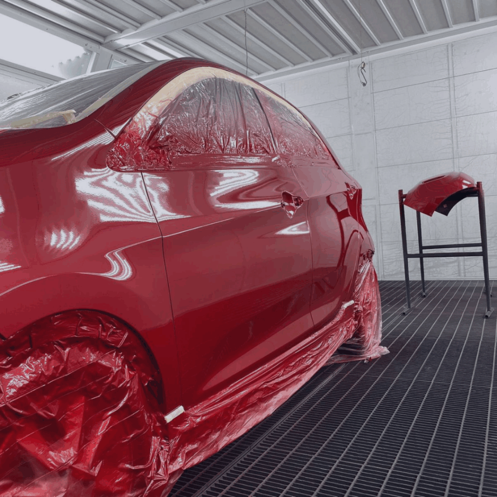 Voiture rouge dans la cabine de peinture de la Carrosserie du Relais SA à Sonceboz-Sombeval, Jura bernois, après application d’une nouvelle peinture automobile.