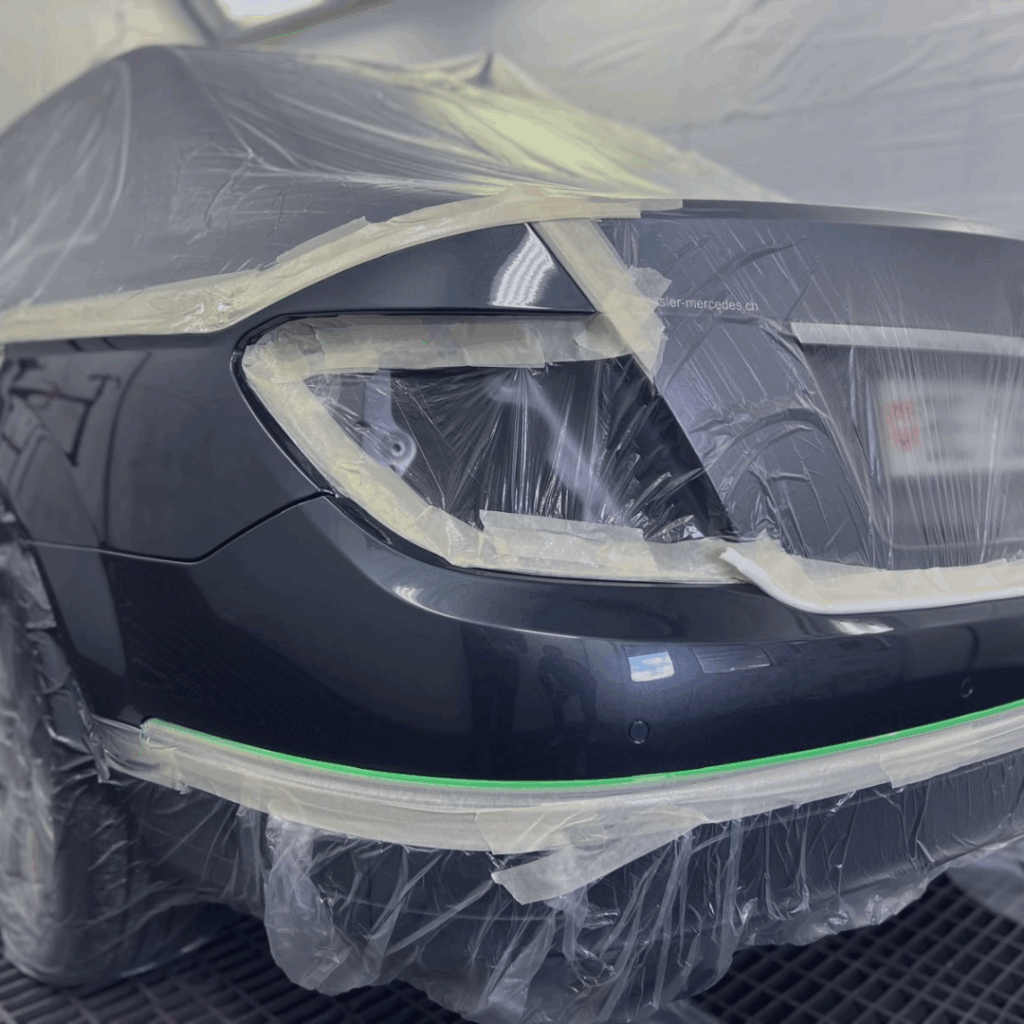 Retouche de peinture sur un pare-chocs arrière dans la cabine de peinture de la Carrosserie du Relais SA à Sonceboz-Sombeval, Jura bernois.