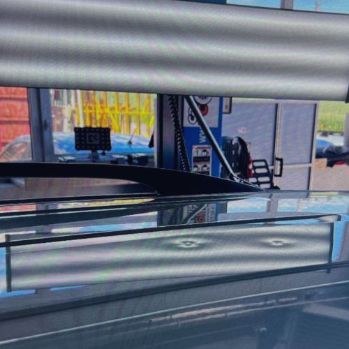 Inspection d’une carrosserie rouge avec lampe de contrôle lors d’un débosselage sans peinture à la Carrosserie du Relais SA à Sonceboz-Sombeval, Jura bernois.